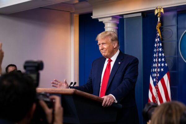 Donald Trump hablando en el podio de la Casa Blanca con banderas estadounidenses, comentando sobre Venezuela